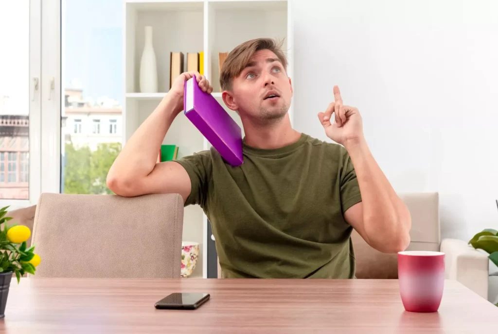 Man holding a book to his head, looking thoughtful, representing a fatigue-friendly lifestyle.