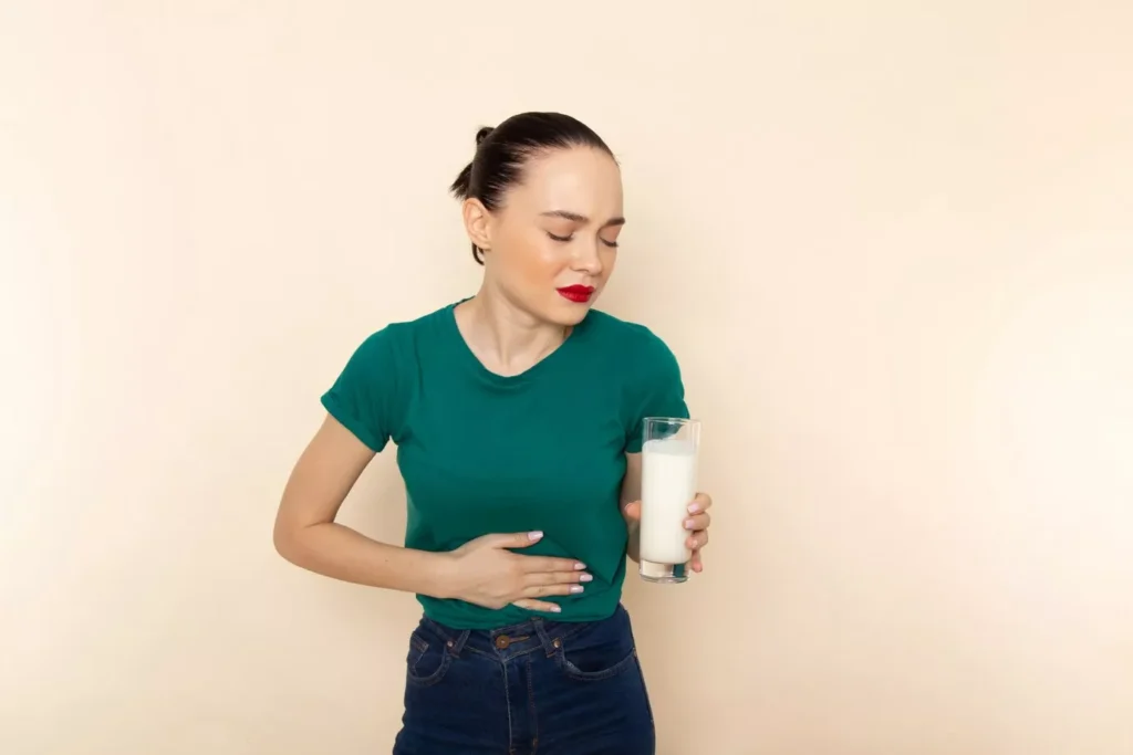 Woman with stomach pain holding milk, possibly lactose intolerant – Nourish Your Gut with Prebiotics.